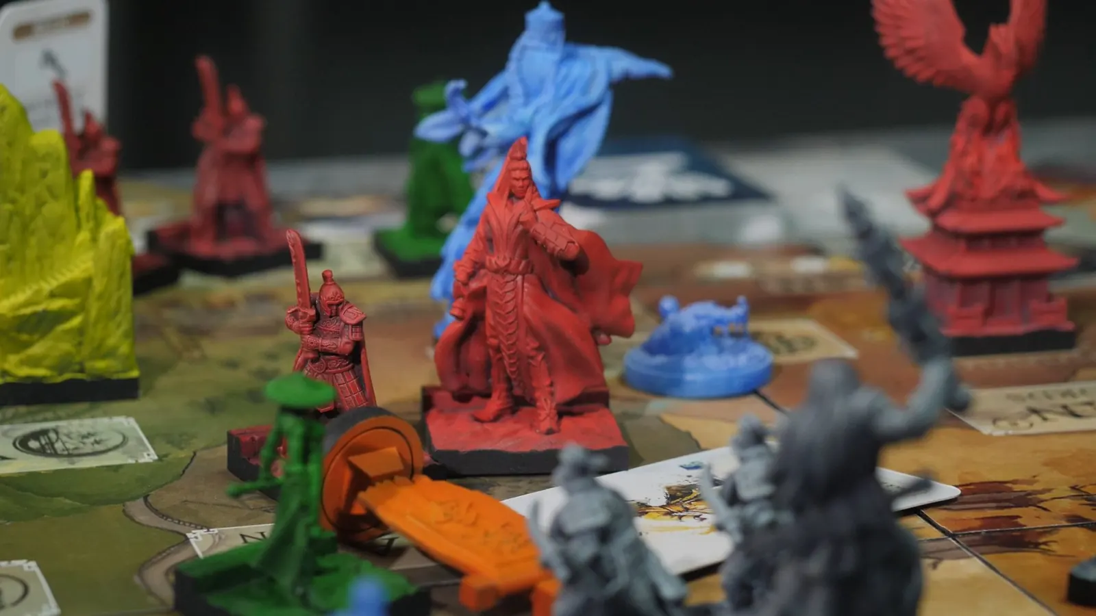 A red robed commander among red, green and blue miniatures, with a phoenix tower behind