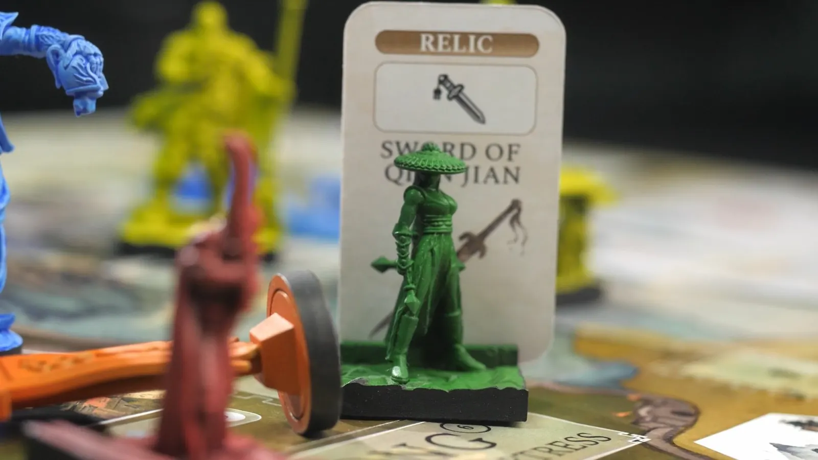 A green figure in a wide hat in front of the Sword of Qian Jian relic card