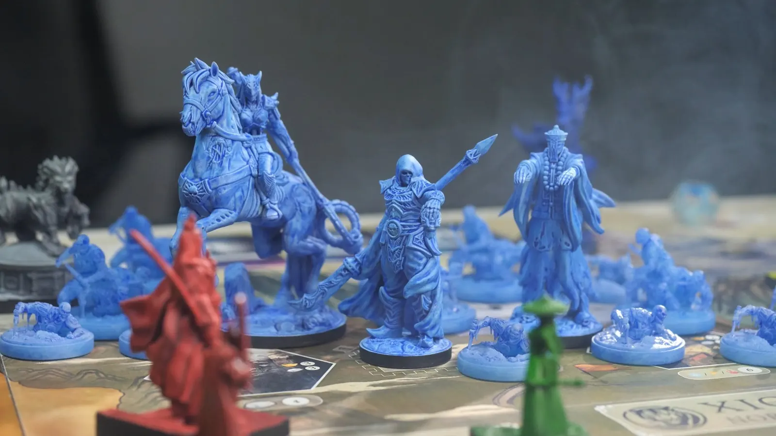 A blue army gathered on the board: a rider, a hooded warrior and a tall robed figure among smaller units