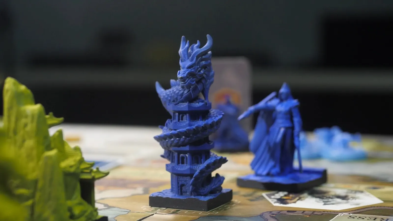 A dark blue dragon coiled around a tower, next to a robed blue figure