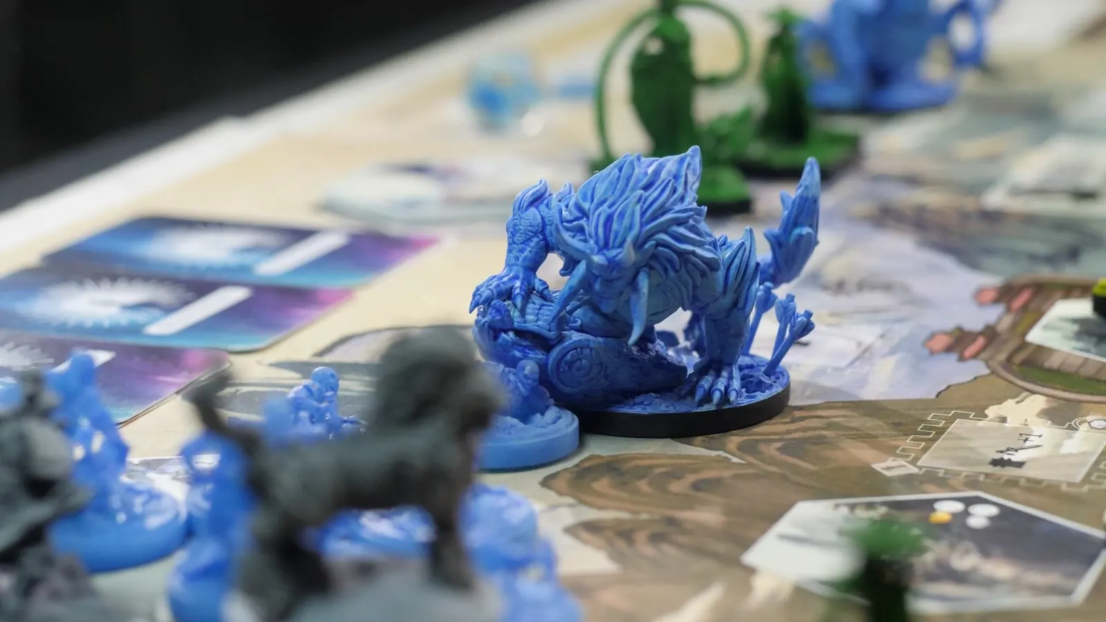 A spiked blue beast miniature on the board, with cards laid out behind it